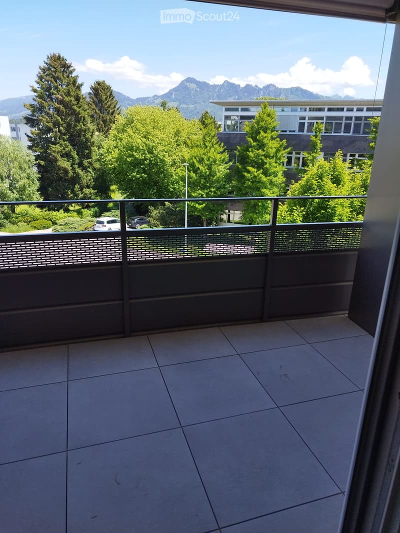 Balcony with tiled floor, metal railing, and scenic mountain view in the background.
