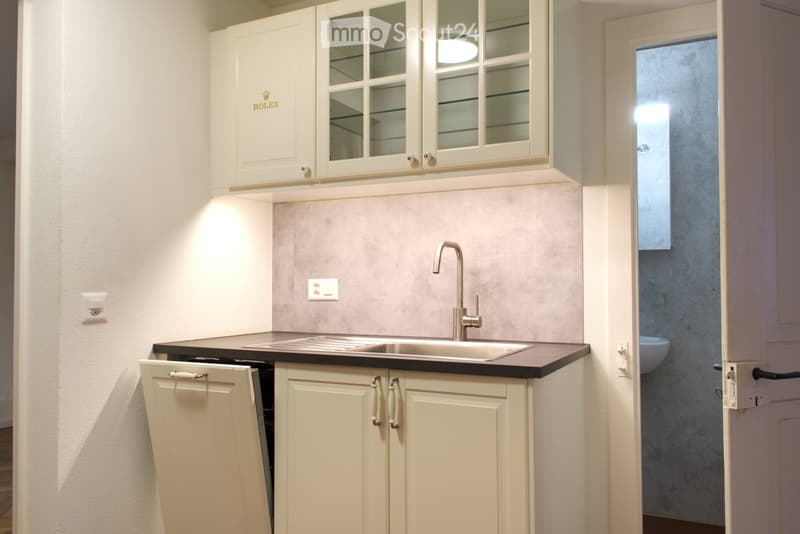 modern kitchen with white cabinets, stainless steel sink, faucet, countertop, electrical outlets, and a small appliance