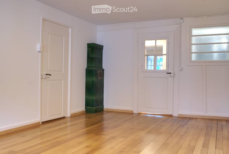 empty room, wooden floor, white walls, two doors, green fireplace