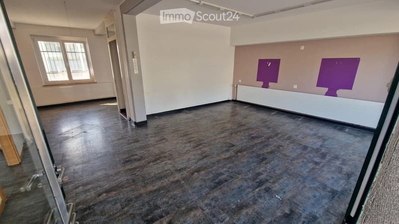 Empty room with wooden flooring, white walls, and large windows. No furniture or equipment present.