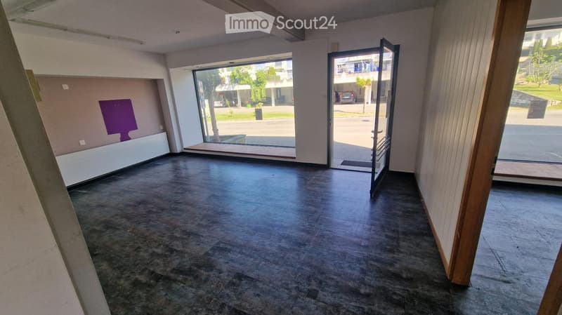 Empty room with dark tiled floor, large glass doors leading outside, and a purple object on the wall.