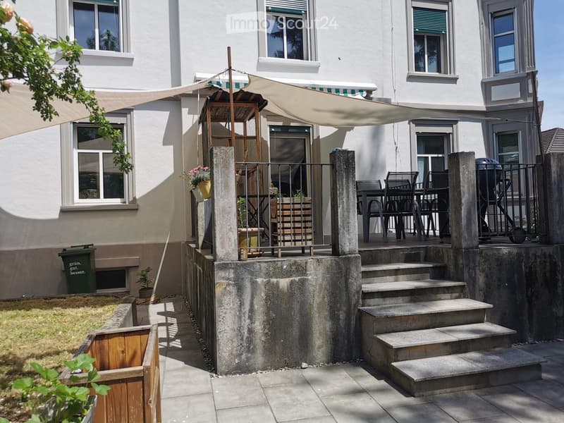 Garden area with steps leading up to a patio, outdoor furniture, and a covered seating area with a canopy attached to the building.