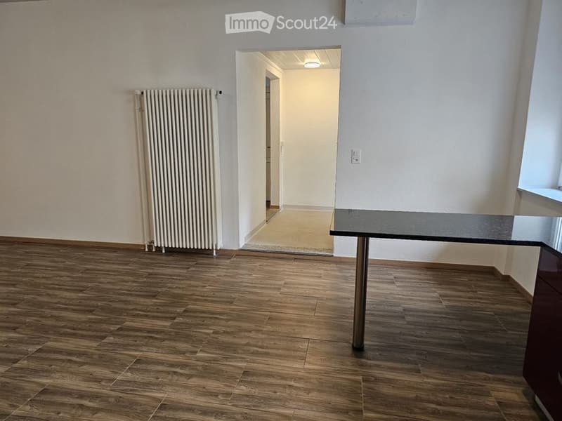 empty room, hardwood floors, radiator, countertop, doorway leading to another room, window