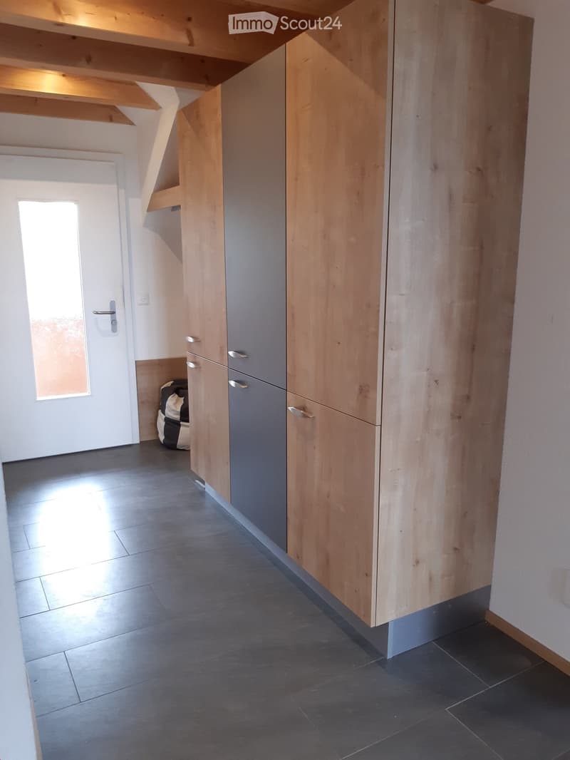 Modern hallway with wooden built-in storage units, grey and light wood finishes, tiled floor, and a small window letting in natural light.