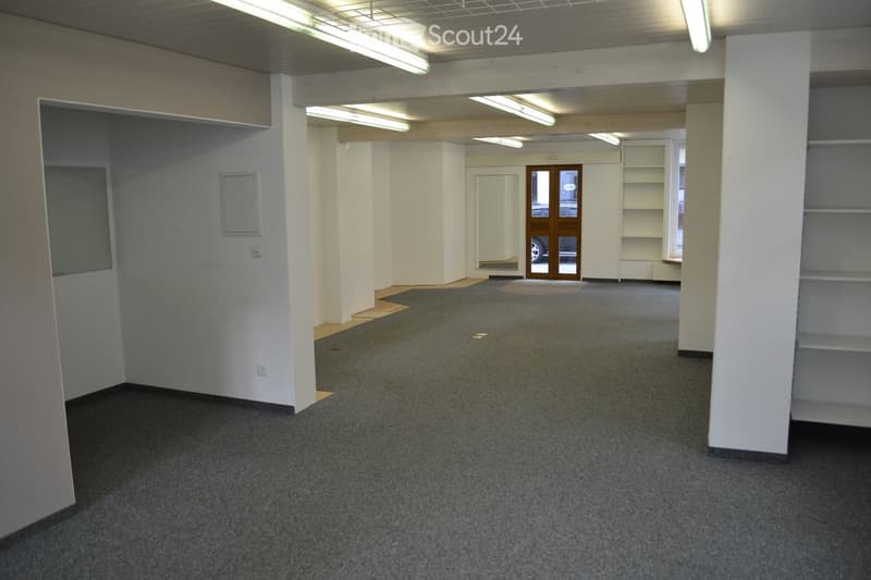 empty room, gray carpet, white walls, wooden beams, white shelves, fluorescent lights