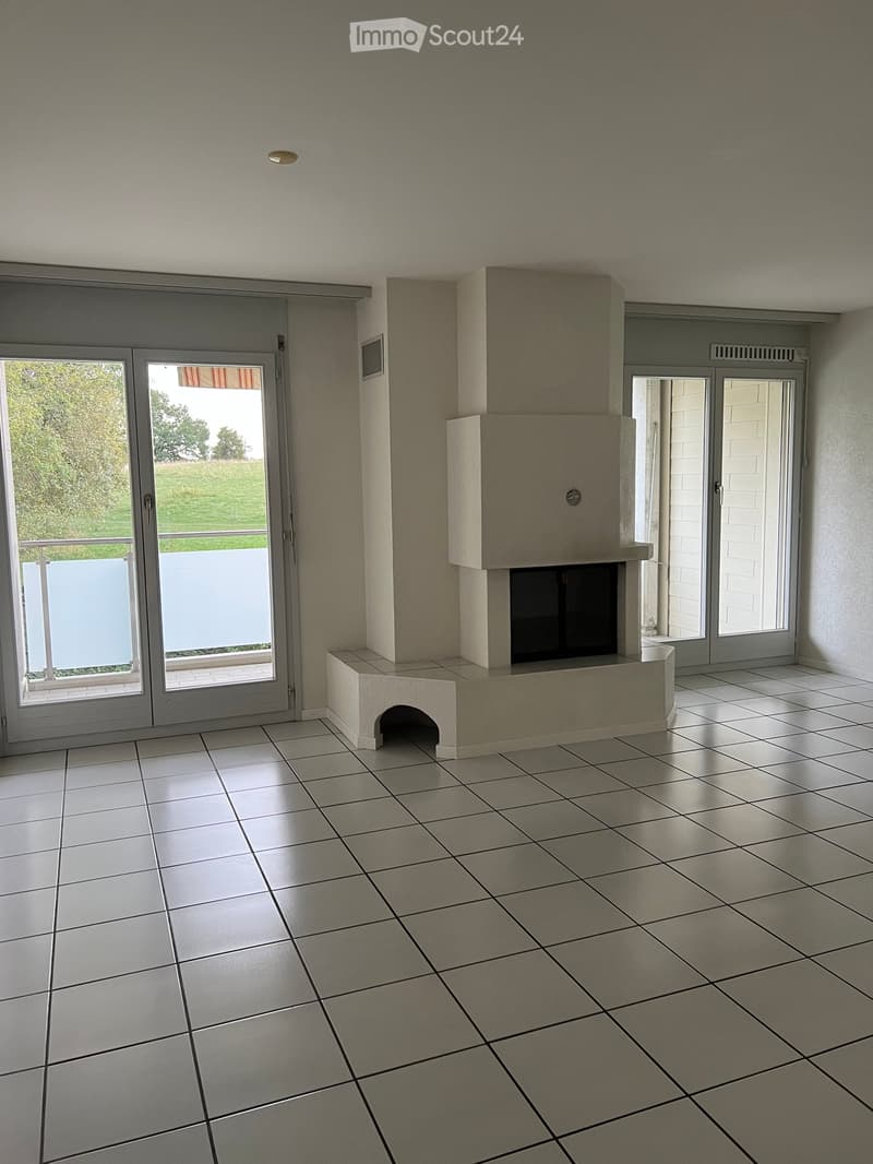 Empty room with tiled floor, fireplace, and large sliding glass doors leading to a balcony.