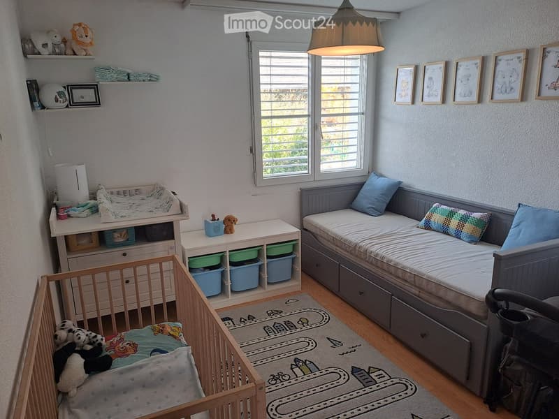 A nursery with a crib, changing table, storage boxes, a daybed, and a rug.