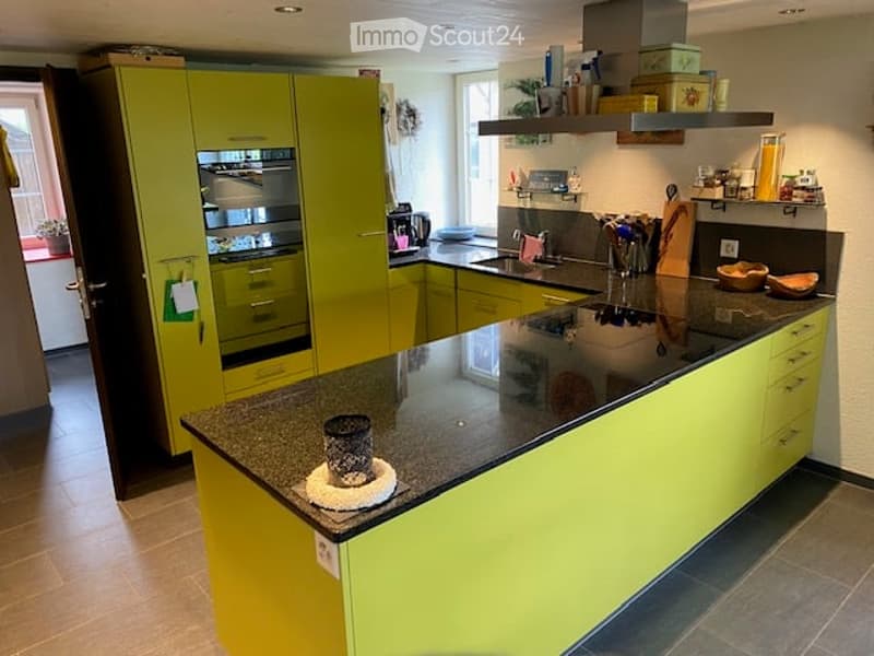 Modern kitchen with bright green cabinets, stainless steel appliances, and a black granite countertop. Features include an oven, sink, and various kitchen items on the counter.