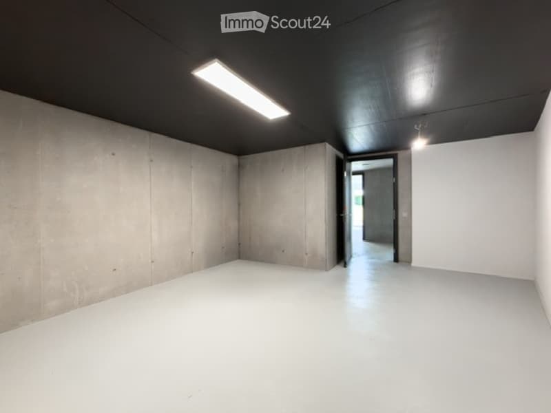 Completely empty room with bare concrete walls, white floor, and recessed lighting. No furniture or equipment.