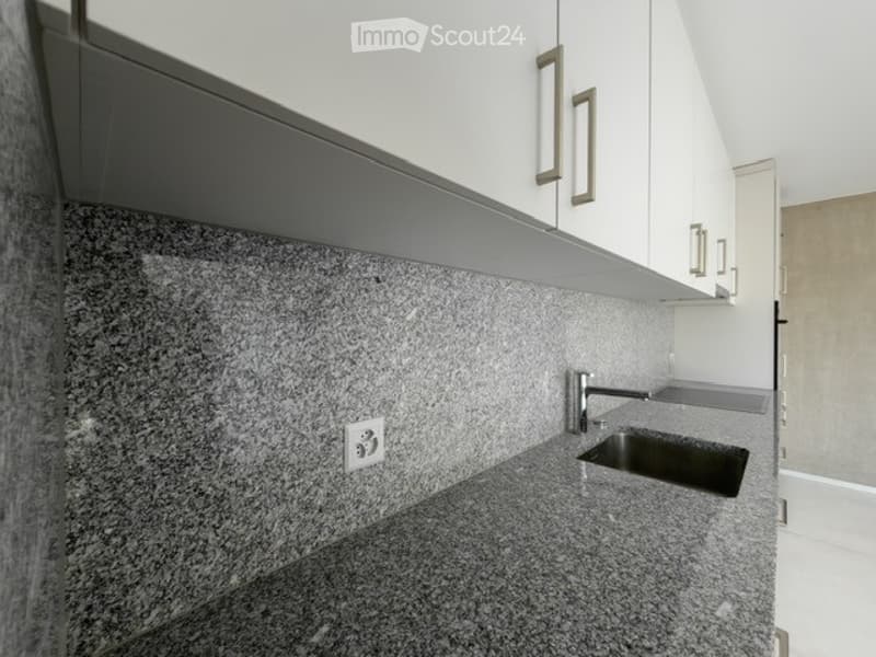Modern kitchen with granite countertops, white cabinets, and a stainless steel sink.