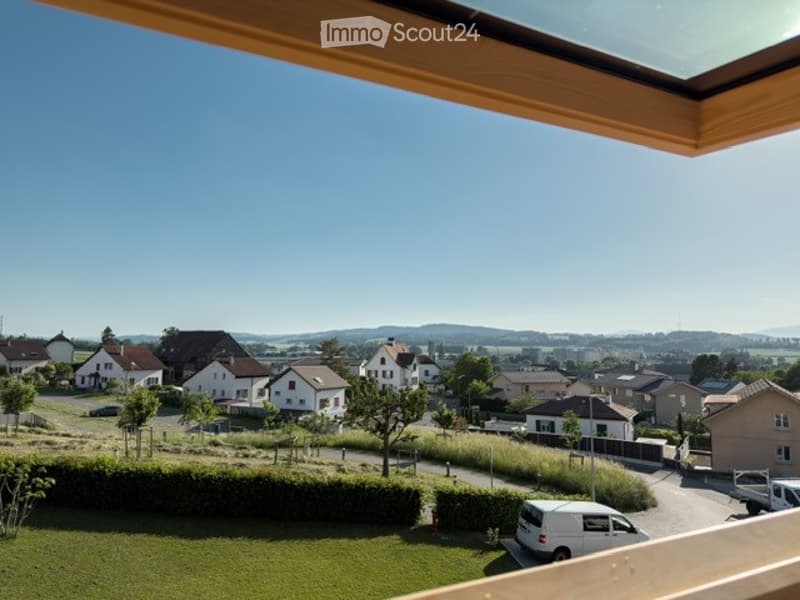 Balcony view overlooking a residential neighborhood with houses, trees, and a clear blue sky.