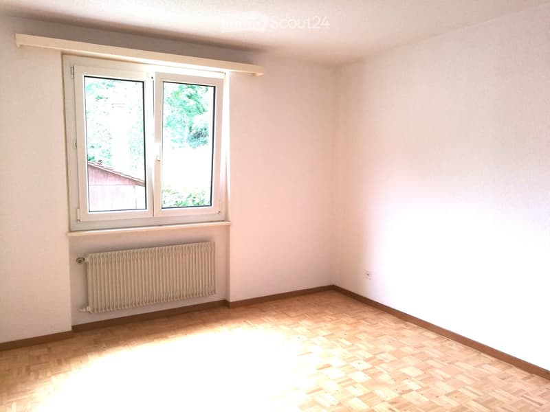 Empty room with light wooden flooring, white walls, and a radiator below a double window. No furniture or equipment present.
