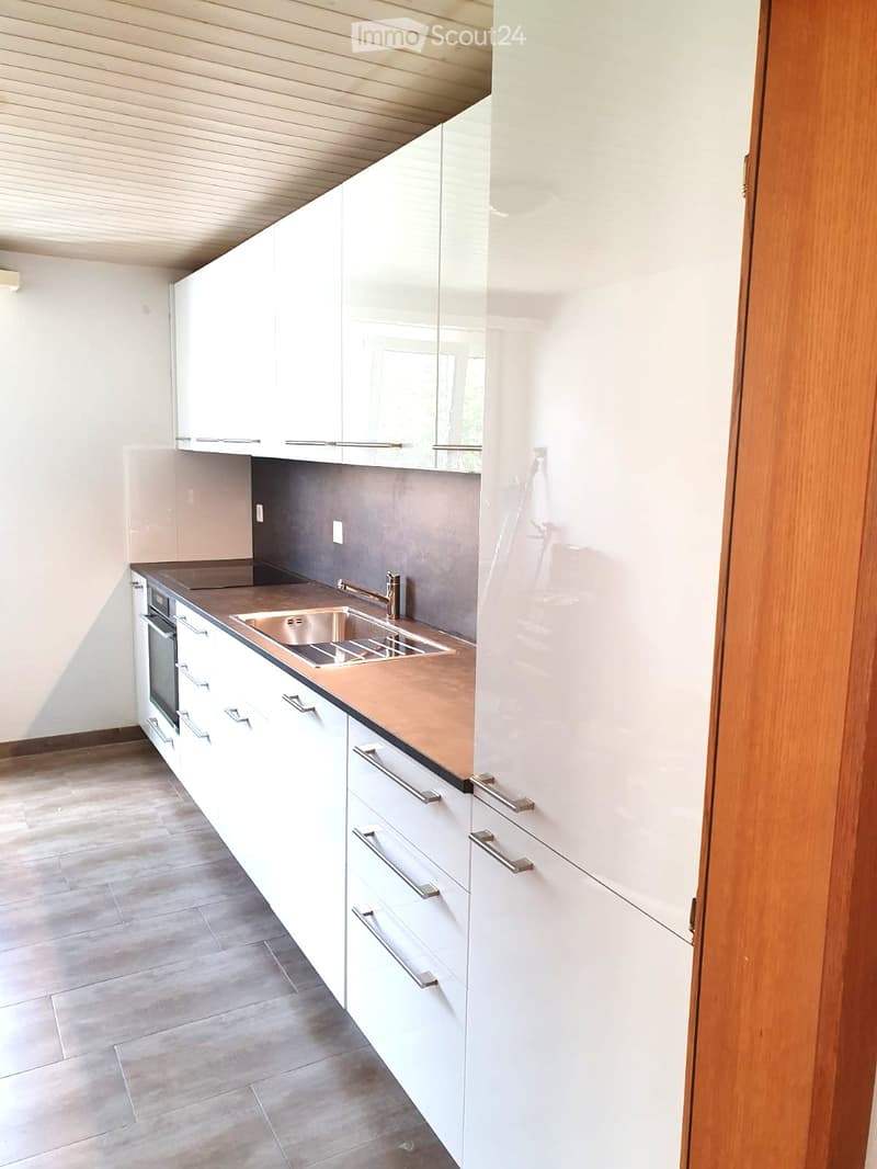 Modern kitchen with white cabinets, stainless steel sink, and copper countertop.