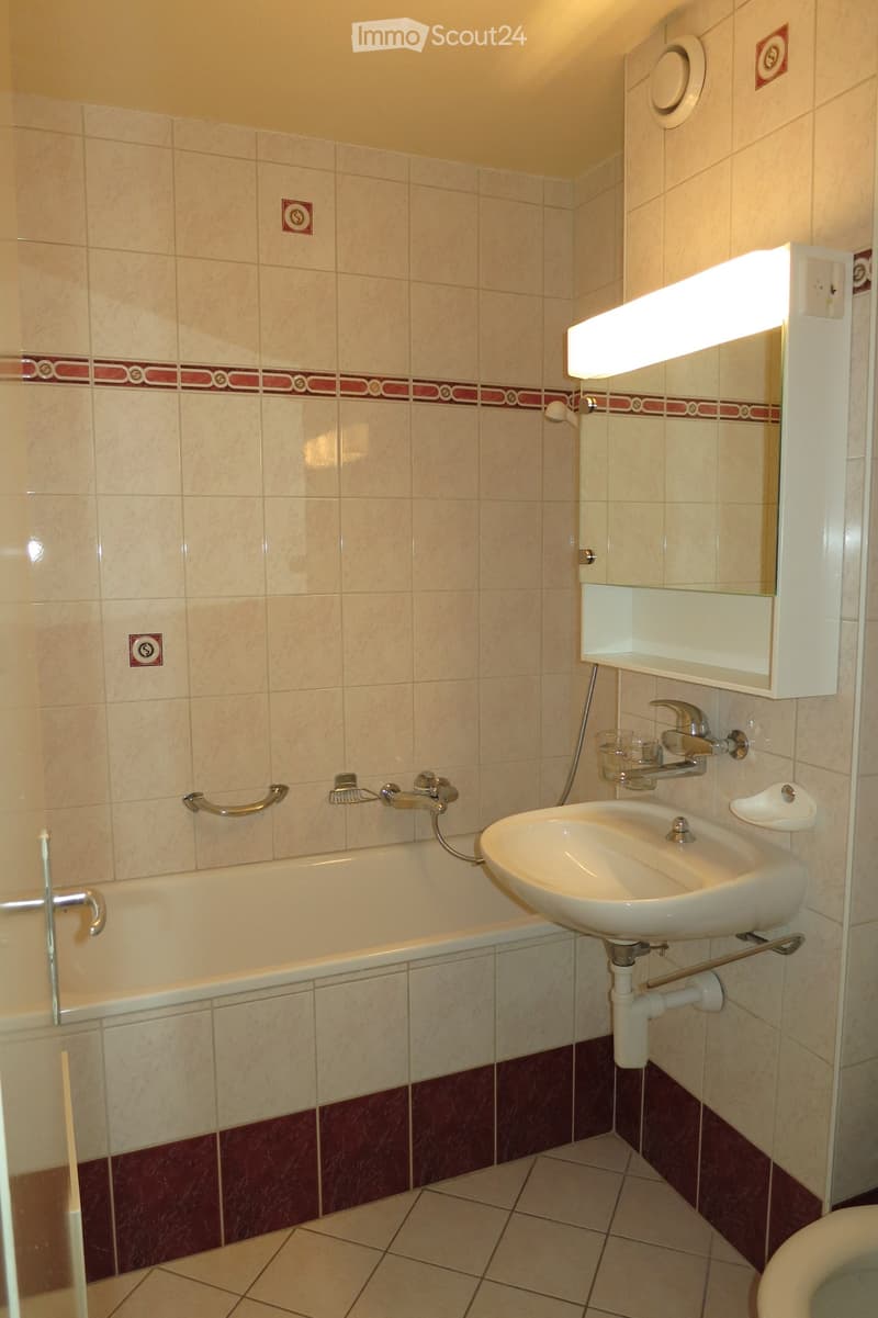 Bathroom: bathtub, sink, mirror, shower, tiled floor, tiles on walls, vanity unit