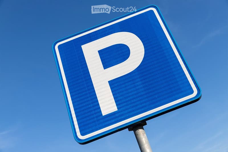 A blue parking sign with a white 'P' symbol, mounted on a metal pole against a clear blue sky.