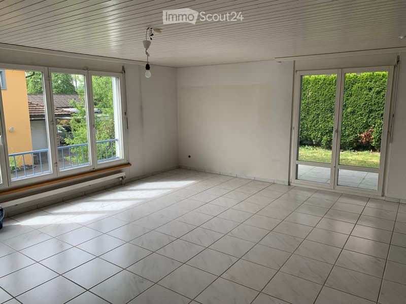 Empty room with large windows, tiled floor, and a hanging light fixture.
