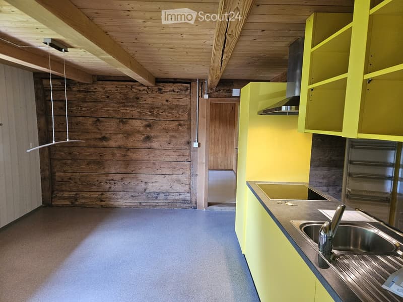 Modern kitchen with yellow cabinets, stainless steel sink, and wooden ceiling beams.