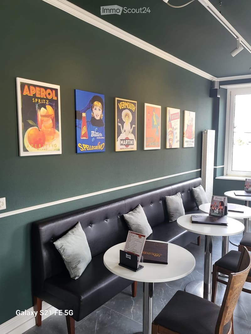 Modern interior with dark green walls, leather sofa, white tables, and vintage-style posters.