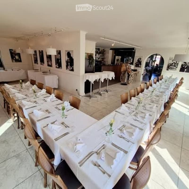 A long, elegant dining setup with multiple tables and chairs, each adorned with white tablecloths, floral centerpieces, and neatly arranged place settings.
