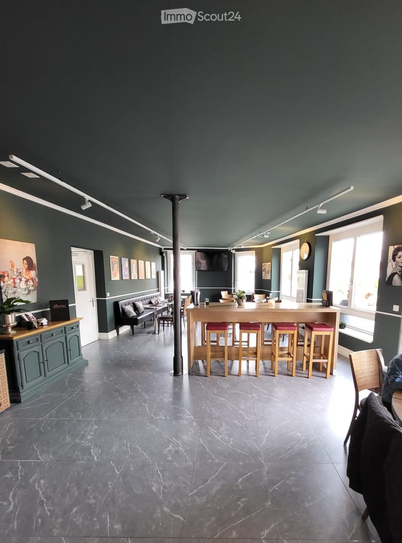 Modern interior with dark green walls, grey marble floor, bar counter with stools, sofa, tables, chairs, and decorative cabinet.