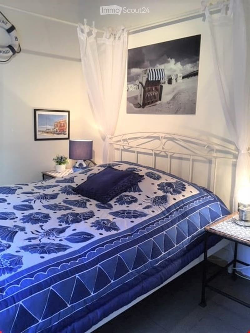 bedroom with bed, nightstand, lamp, picture frame, lifebuoy, table with flower vase