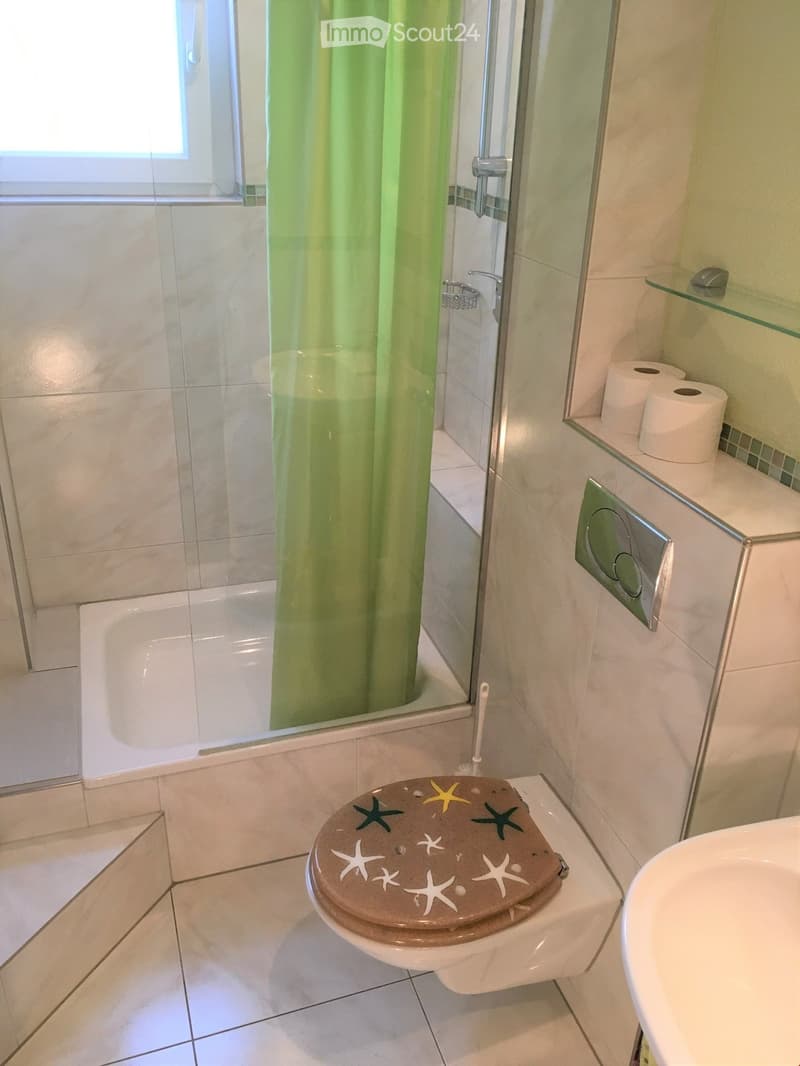 Bathroom with shower, toilet, sink, and green shower curtain