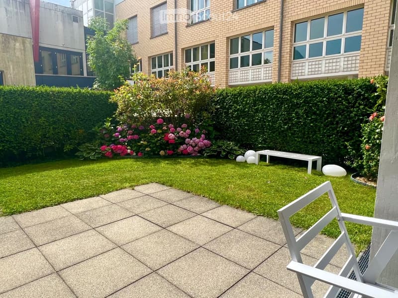 Garden with green lawn, white bench, white chair, and decorative white sculptures.