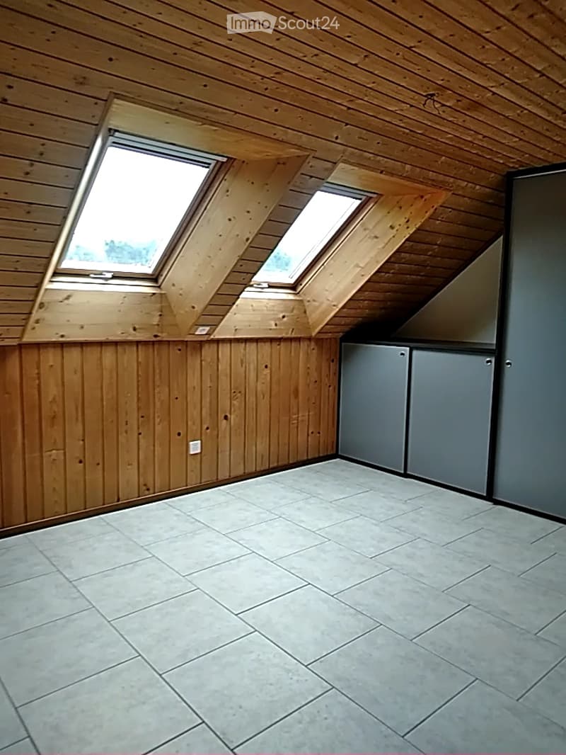 Spacious hallway with wooden flooring and walls, featuring large windows on one side and a modern, grey ceiling panel design.