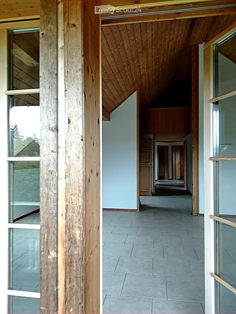 Empty hallway with wooden ceiling, tiled floor, and glass-paneled doors leading to other rooms.