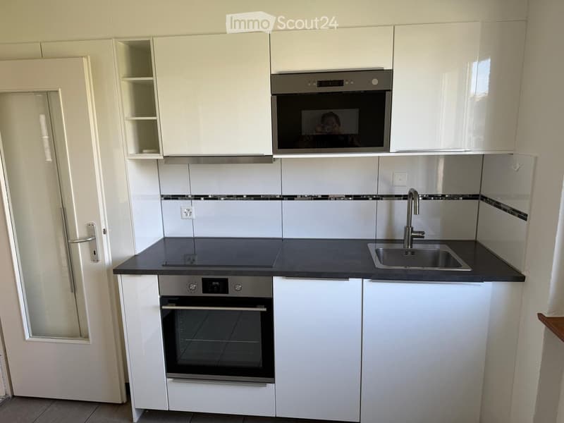 Modern kitchen with white cabinets, stainless steel appliances, and a black countertop.