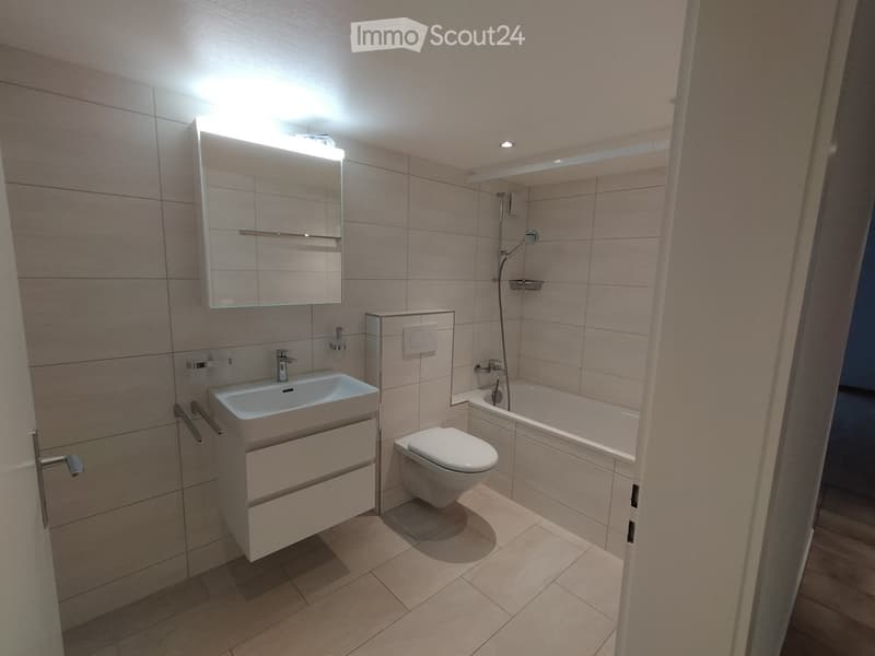 Bathroom with white tile walls, sink, toilet, bathtub with shower, mirror, wooden floor