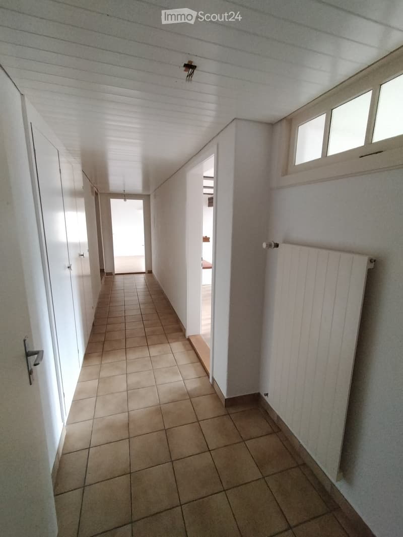 tiled floor, white doors, hallway, radiator, natural light