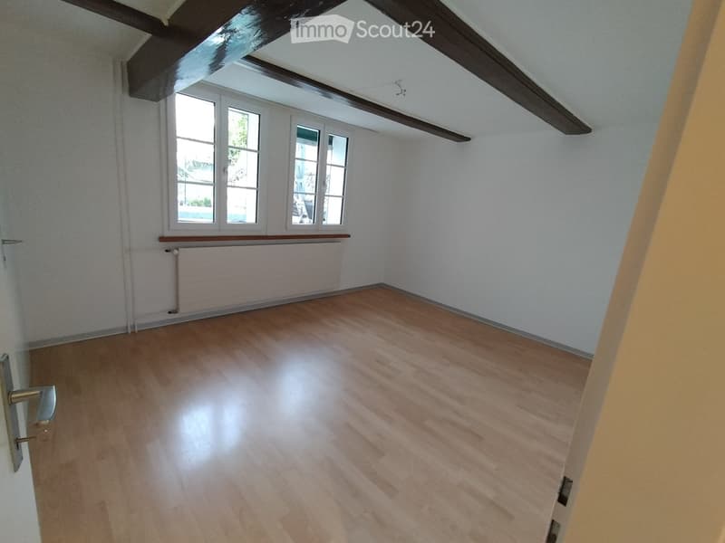 empty room, white walls, wooden floor, three windows, wooden beams on ceiling