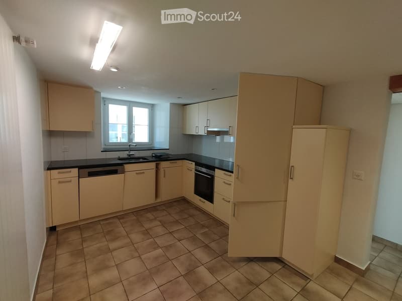 modern kitchen with tan cabinetry, tile flooring, dishwasher, oven, sink, faucet, black counter tops