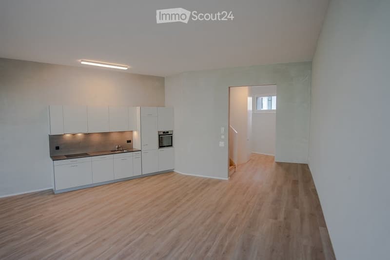 empty kitchen with built-in appliances, white cupboards, wooden floor