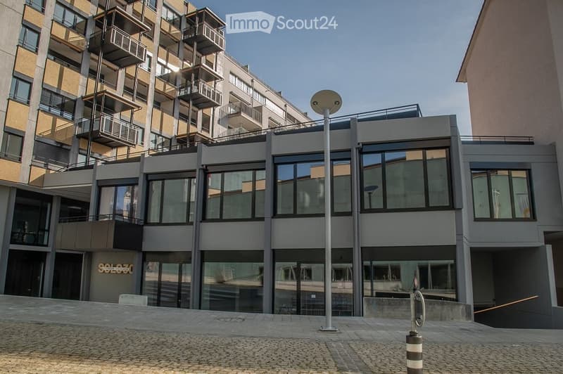 multi-story building, glass windows, metal balconies, ground floor