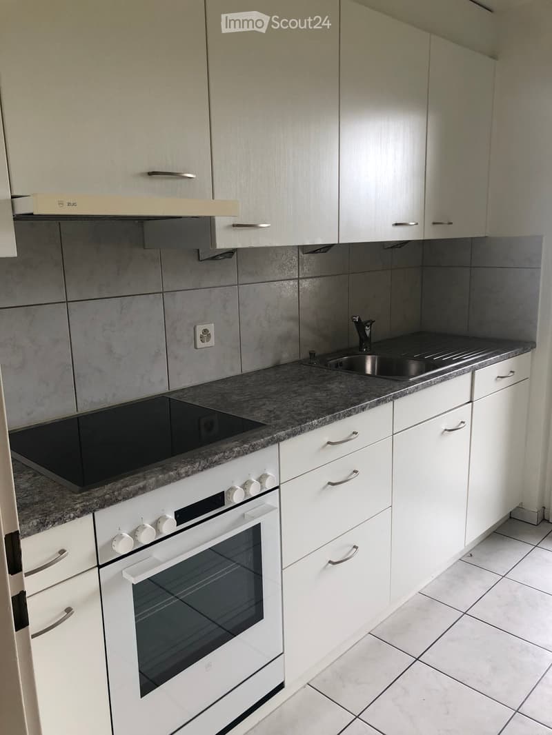 Modern kitchen with white cabinets, granite countertop, built-in oven, and stainless steel sink.
