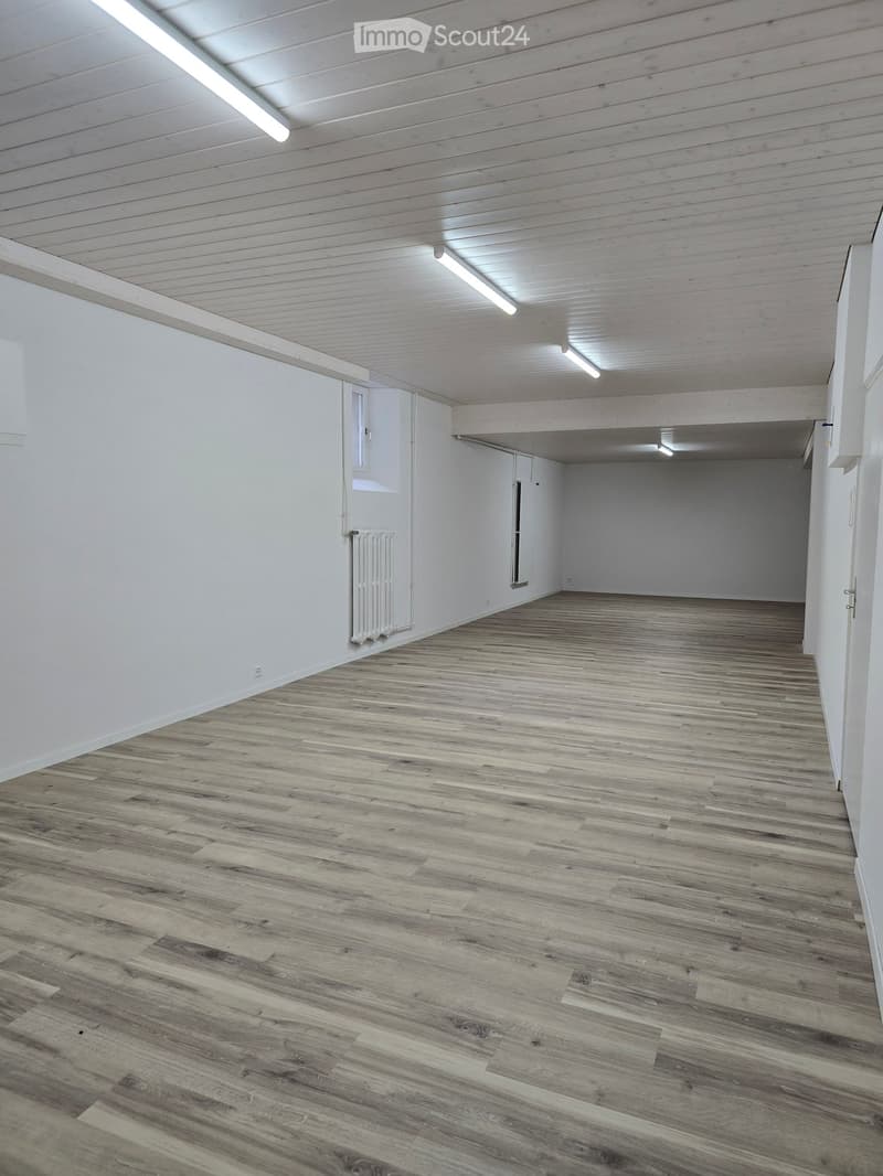 Empty room with wooden flooring, white walls, and exposed wooden ceiling beams. No furniture or equipment present.
