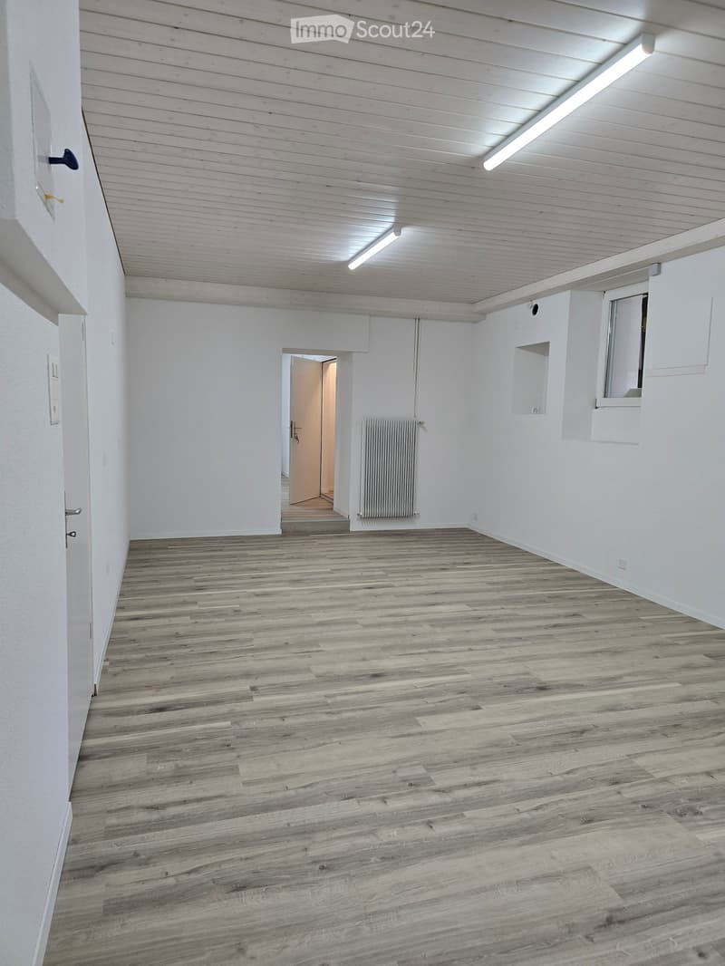 Empty room with wooden flooring, white walls, and a radiator. No furniture or equipment is present.