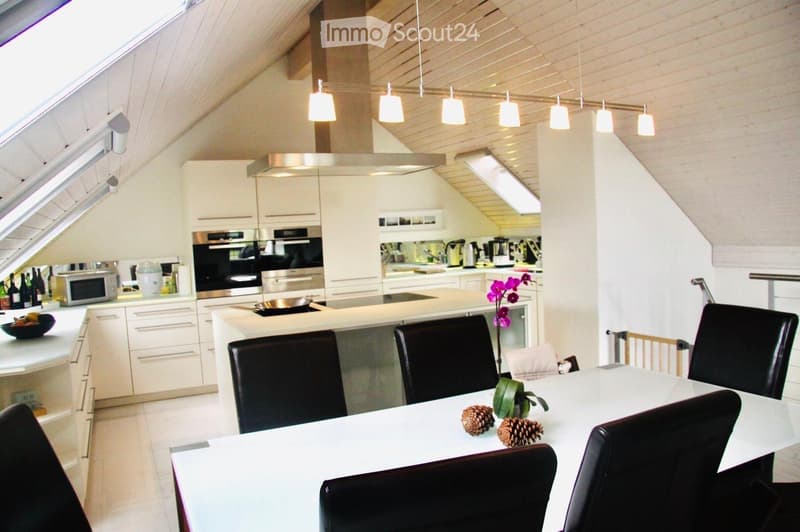 Modern kitchen with white cabinets, stainless steel appliances, island with seating, and pendant lighting.