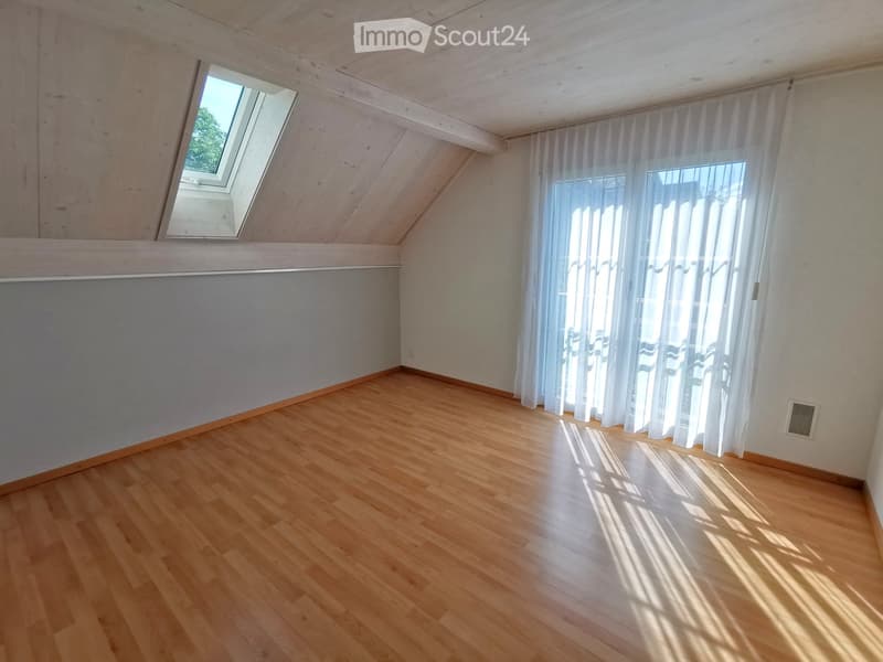 Empty room with wooden flooring, white walls, large window with white curtains, and a skylight window at the top.