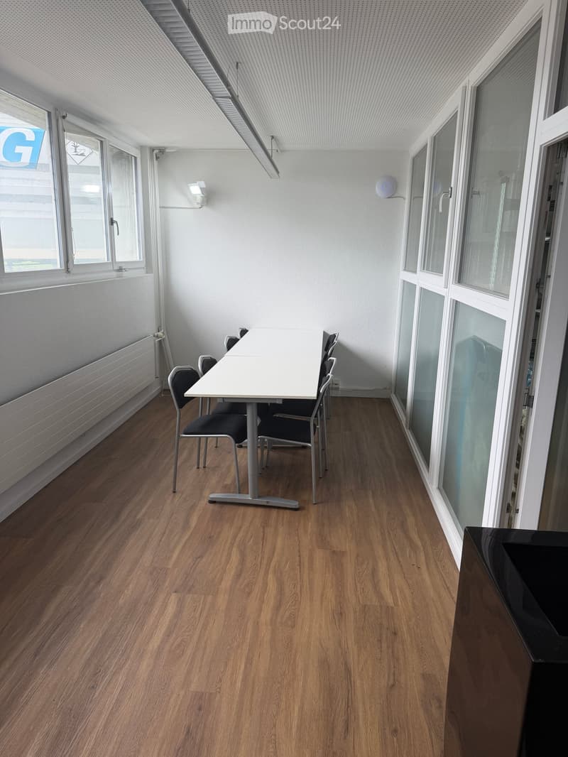 Bright, modern room with wooden flooring, large windows, and a white table with chairs.