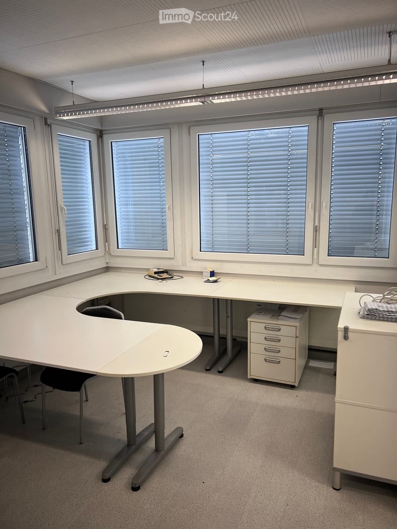 an office space with white desk, white drawers, office chair, and white ceiling lamp