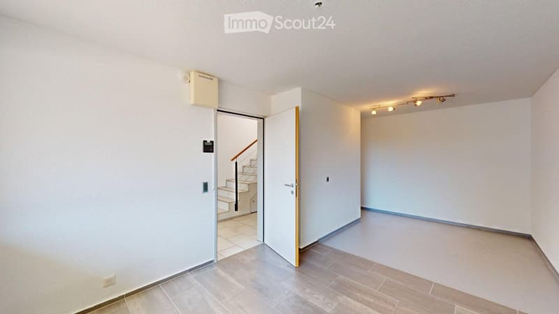 Empty room with white walls, tiled floor, and a door leading to a staircase. No furniture or equipment present.