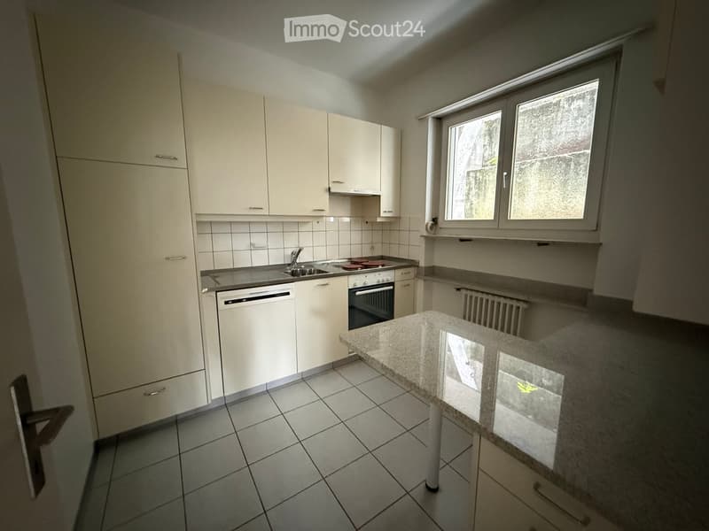 Modern kitchen with white cabinets, tiled floor, granite countertop, sink, oven, and dishwasher.