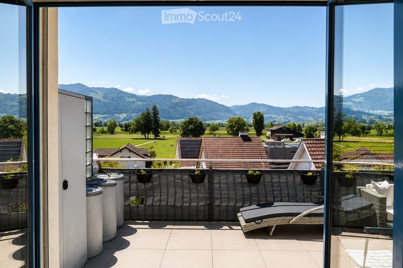 Balcony with lounge chairs, potted plants, and a scenic mountain view.
