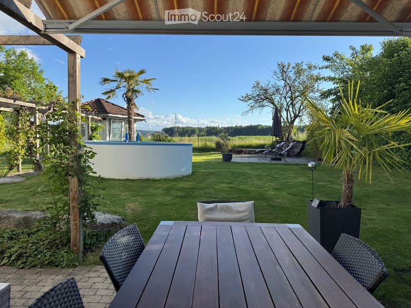 Well-maintained garden with a swimming pool, outdoor dining area, and lounge chairs.