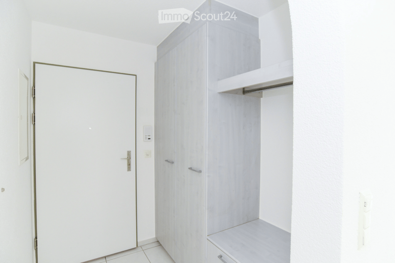Empty room with white walls, tiled floor, and built-in closet with shelves and drawers.