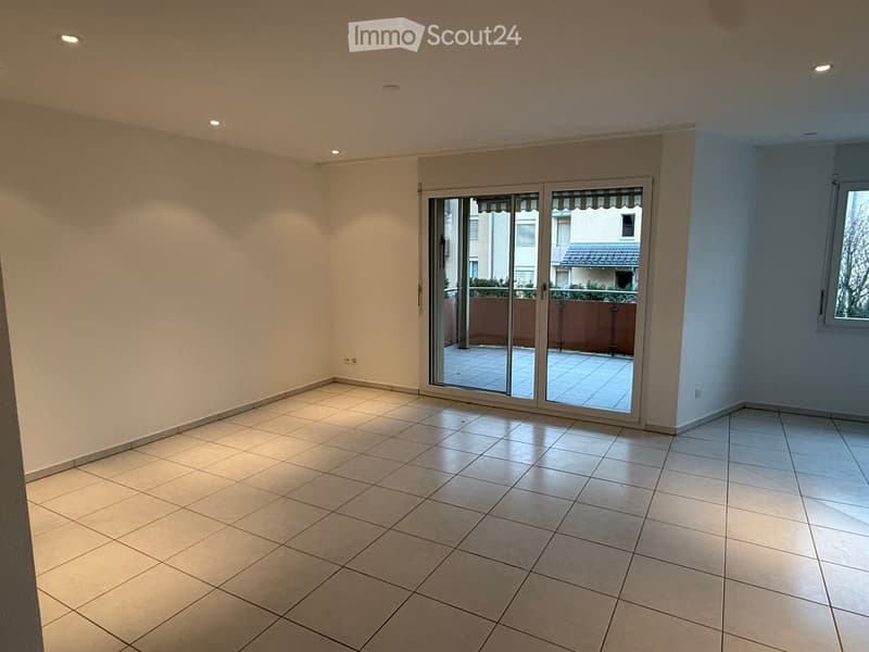 Empty room with tiled floor, white walls, and large sliding glass doors leading to a patio.