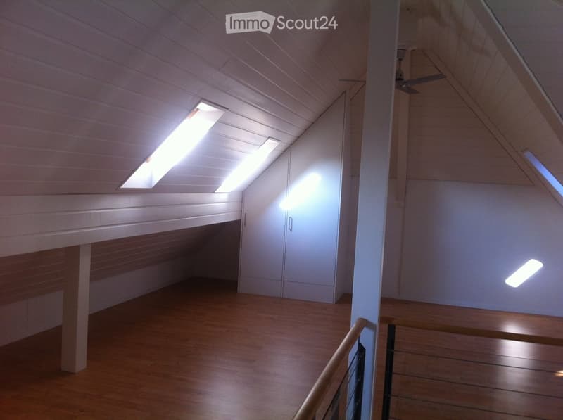 Empty attic space with wooden floors, white walls, skylights, and built-in storage cabinets.